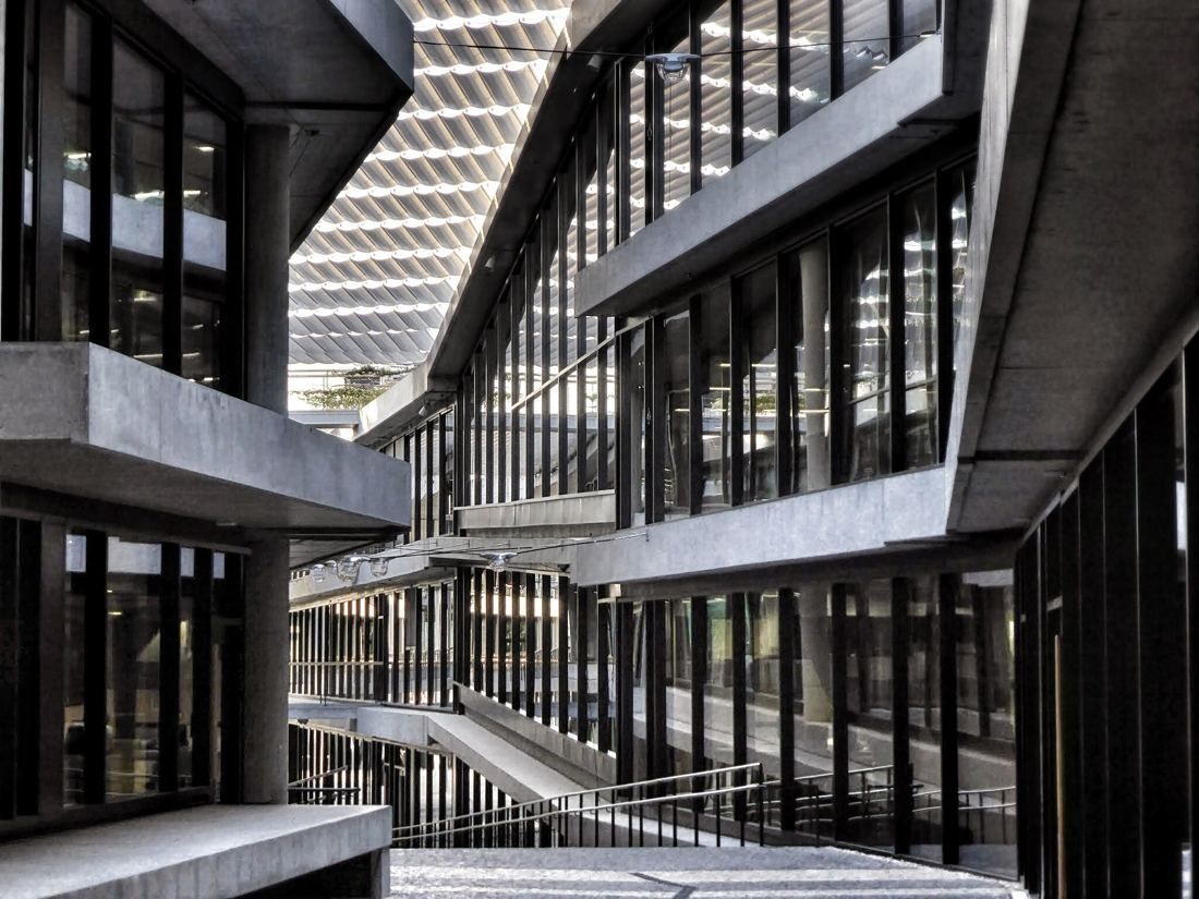 BBVA: Atrium with stacked glazed floors and a staircase seen through a concrete frame