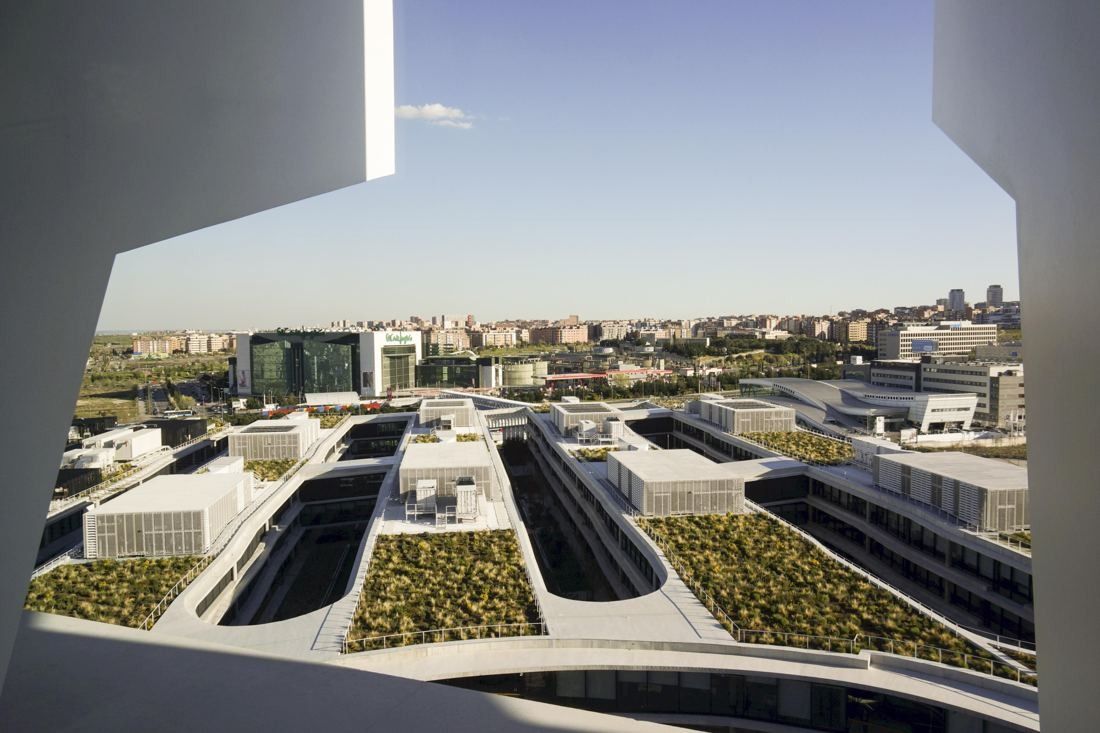 BBVA: View through a large opening over green roofs of the low-rise buildings toward the city