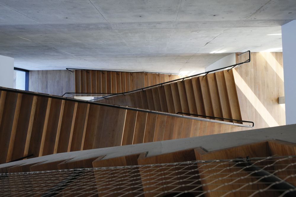 BBVA: Wooden staircase seen from above inside a concrete hall