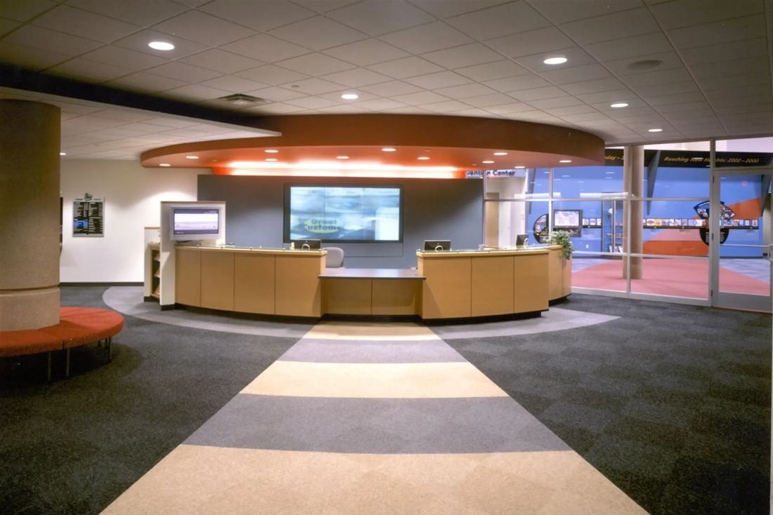 Best Buy: Curved reception desk with a large screen behind it at the end of a patterned carpet