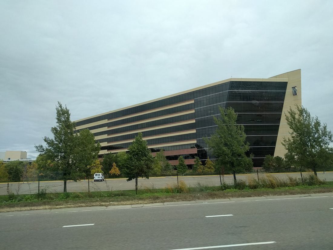 Best Buy: Long banded office building with a pointed end, trees along the road in front