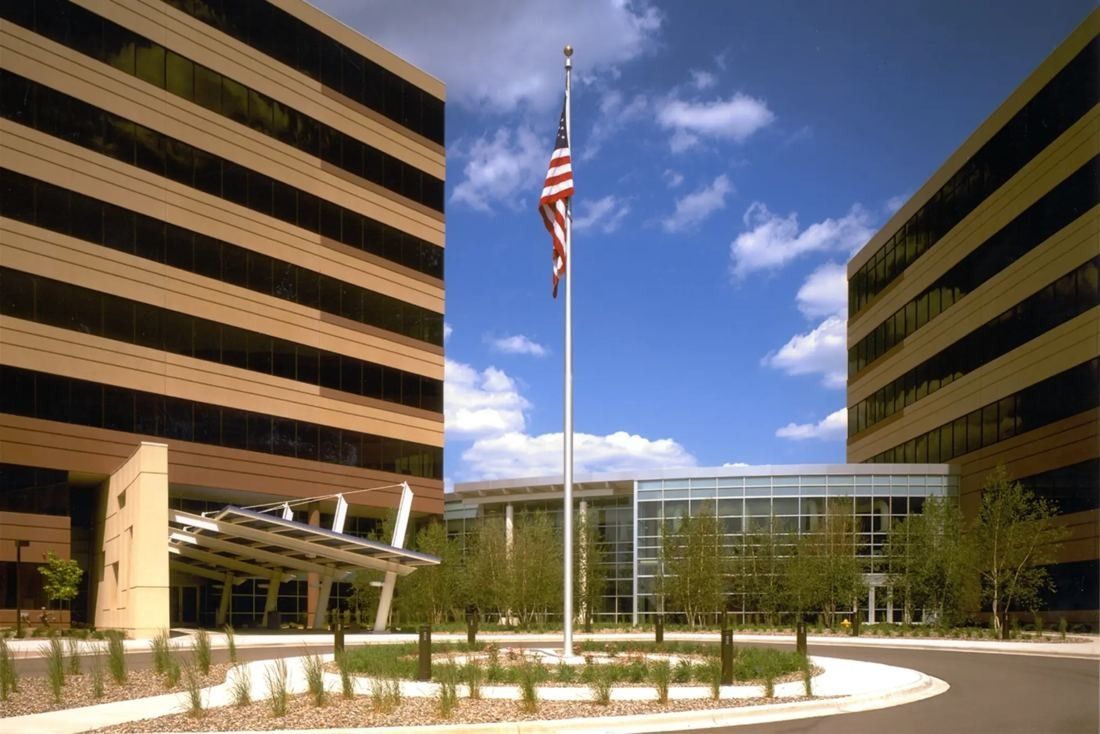 Best Buy: Plaza with a flagpole and a curved drive between two banded office towers and a glass entrance
