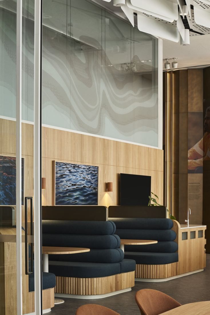 BHP: Booth seating in blue upholstery under a textured wall and glass partition
