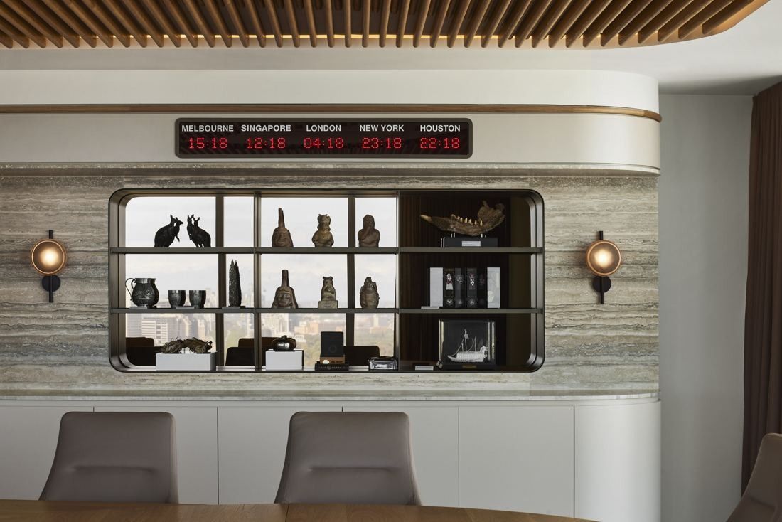 BHP: Curved travertine wall with a lit display niche of objects and a row of world-city clocks