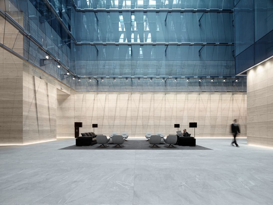 BHP: Large stone-clad lobby under a glass roof with a few lounge chairs