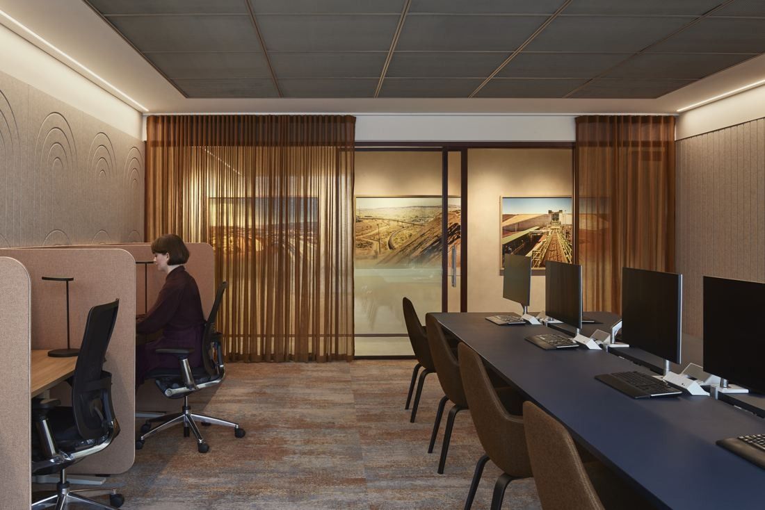 BHP: Long desks with monitors in front of sheer bronze curtains and landscape photographs