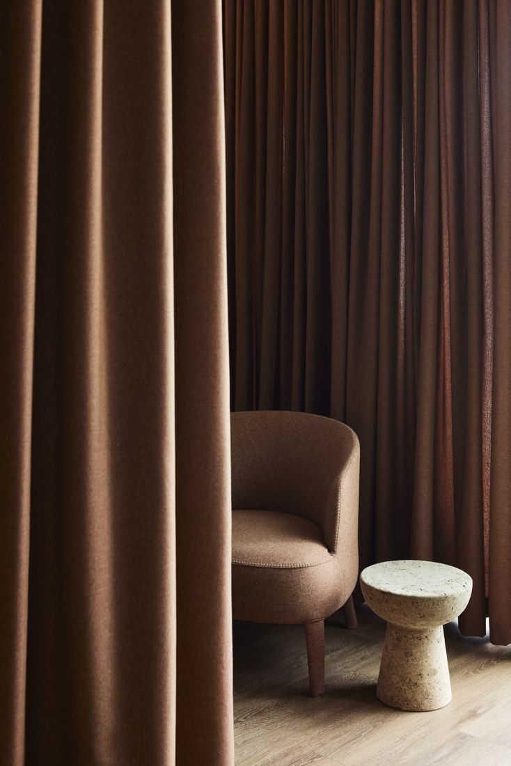 BHP: Quiet corner with an armchair and side table enclosed by brown curtains