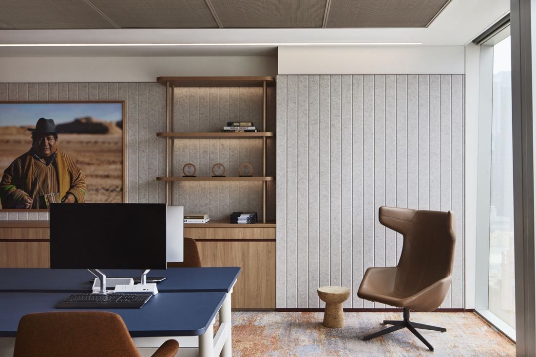 BHP: Workstation with a monitor, a wingback chair and timber shelving beside a large window