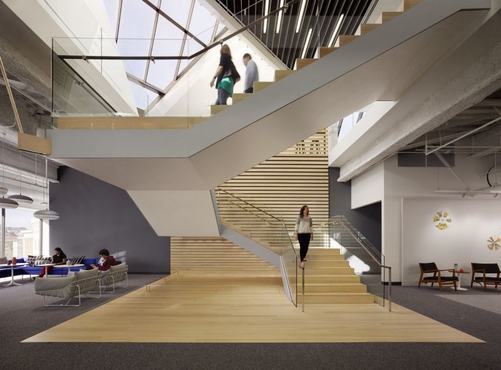 A wide timber stair rising through a skylit atrium