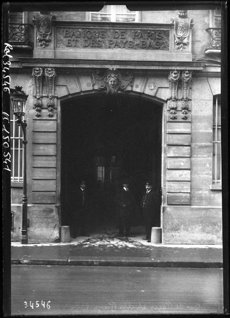 Black-and-white photo of a large arched carriage entrance in a stone facade