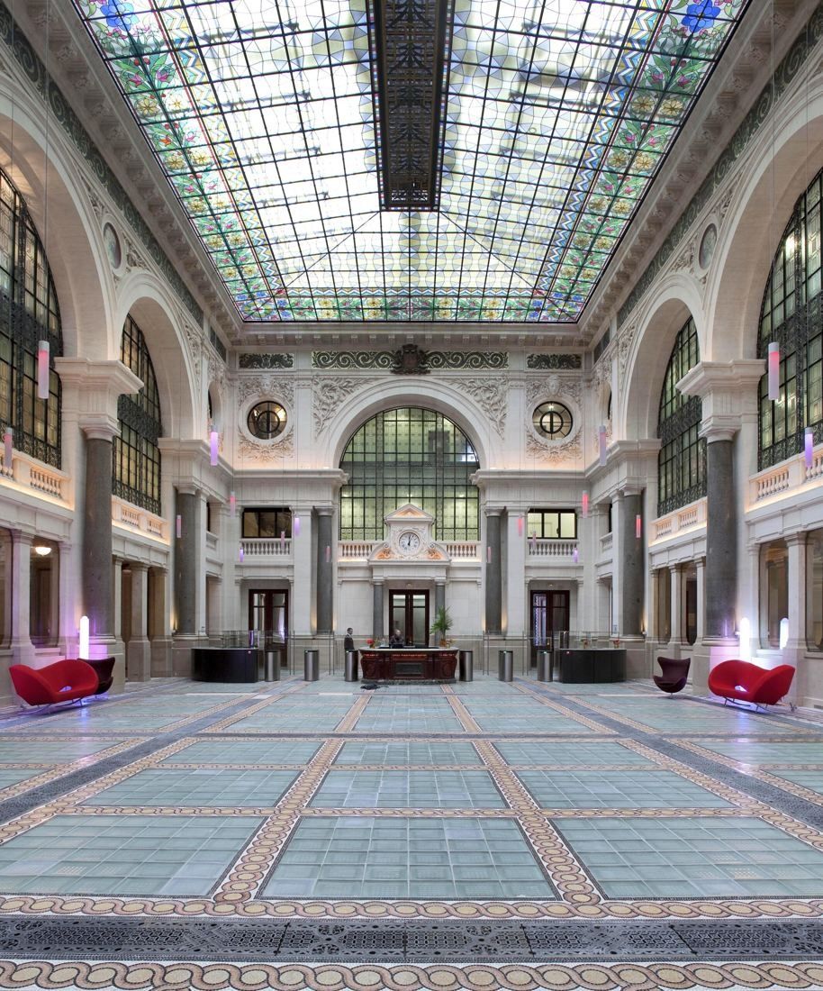 Large glass-roofed atrium with arched windows and mosaic floor