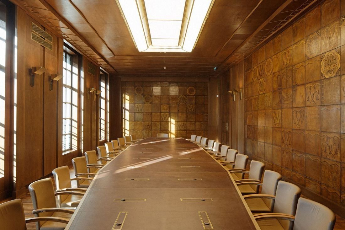 BNP Paribas: Long wood-panelled boardroom with a long table and rows of chairs under a ceiling light strip