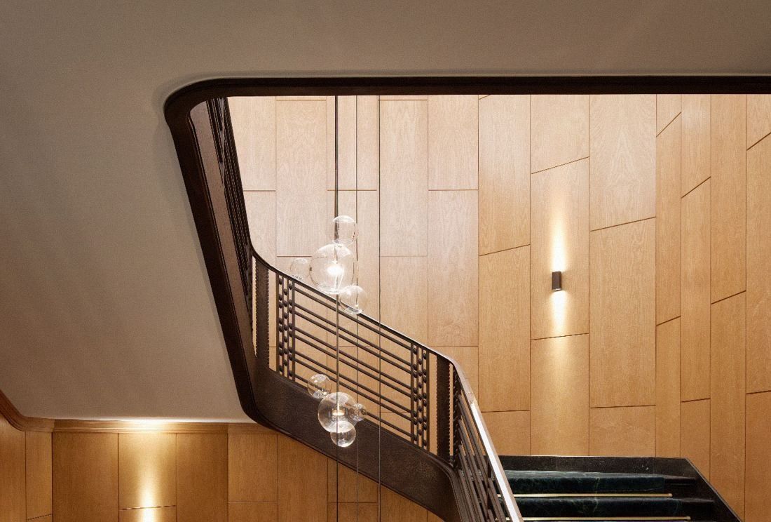 BNP Paribas: Stairwell with a dark metal railing, wood-panelled walls and glass pendant lights