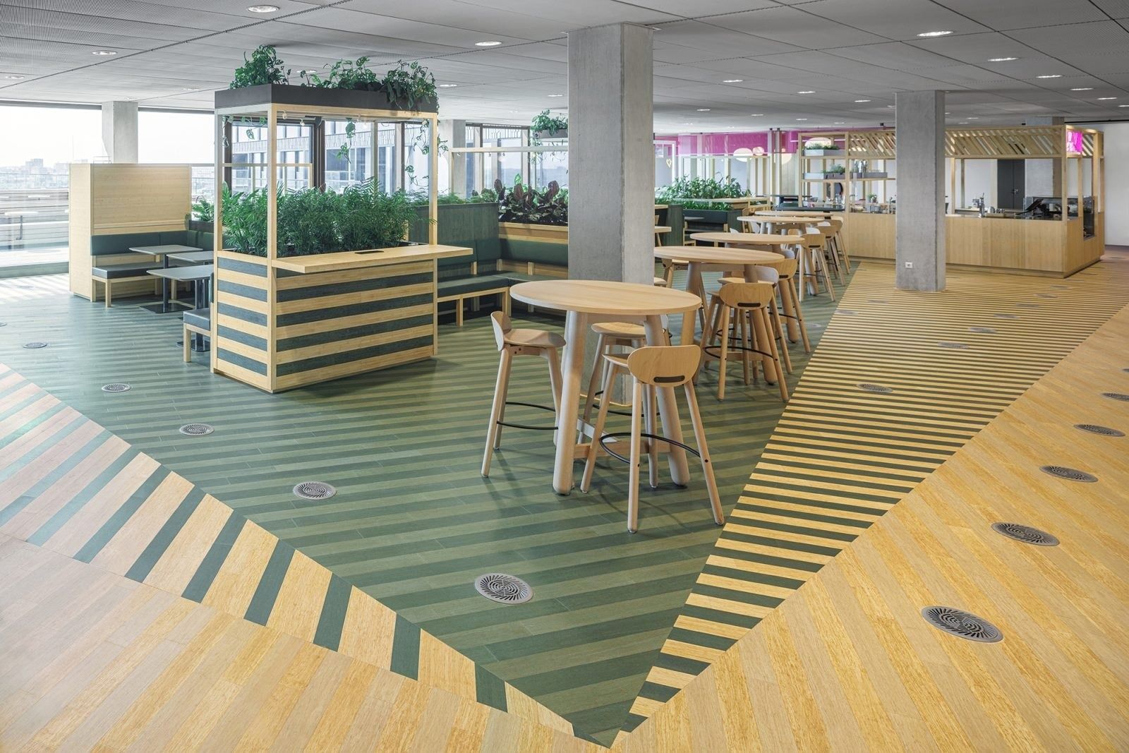 Booking Holdings: Green-striped floor with high tables and planter frames