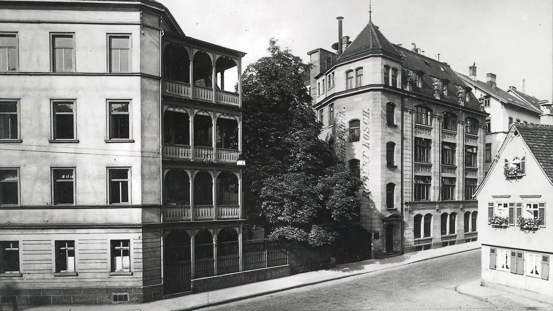 Black-and-white photo of a multi-storey stone building with bay windows on a street corner