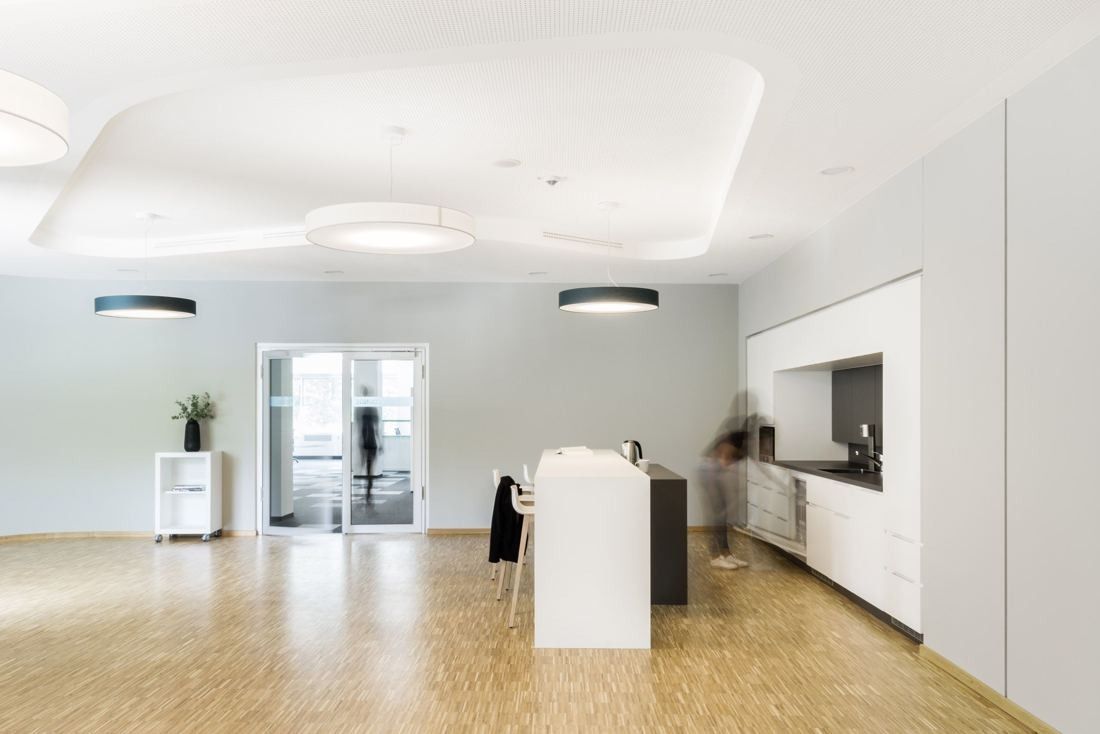 Bosch: Bright open area with parquet floor, round ceiling lights and a white kitchen counter