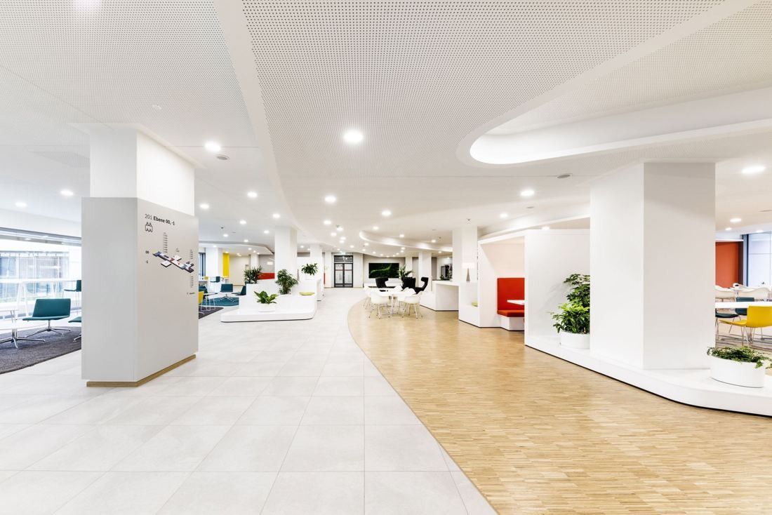 Bosch: Bright open-plan floor with white curved ceilings, light parquet and colourful lounge furniture