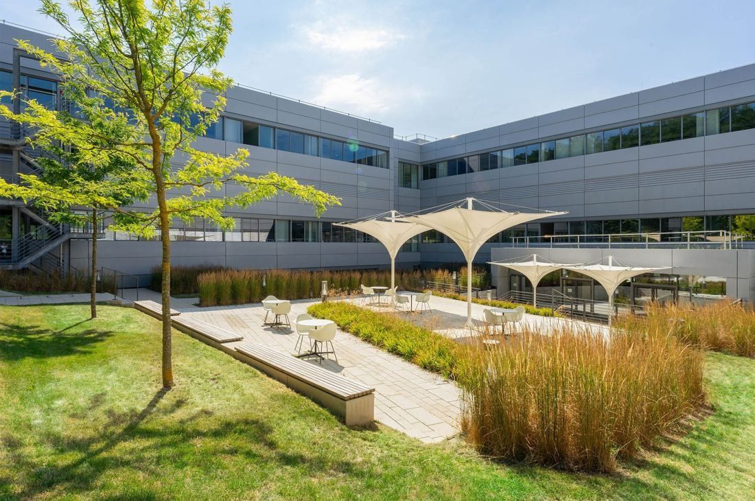Bosch: Landscaped courtyard with grasses, trees and white sail canopies between grey office wings