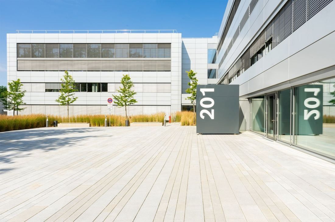 Bosch: Light timber-decked plaza in front of white office façades with a grey sign reading 201