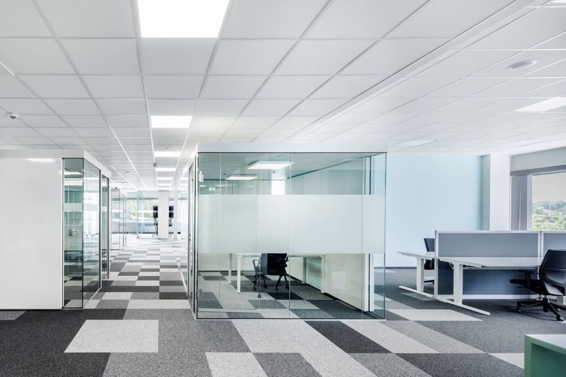 Bosch: Open office floor with glass-walled meeting rooms, white desks and grey patterned carpet