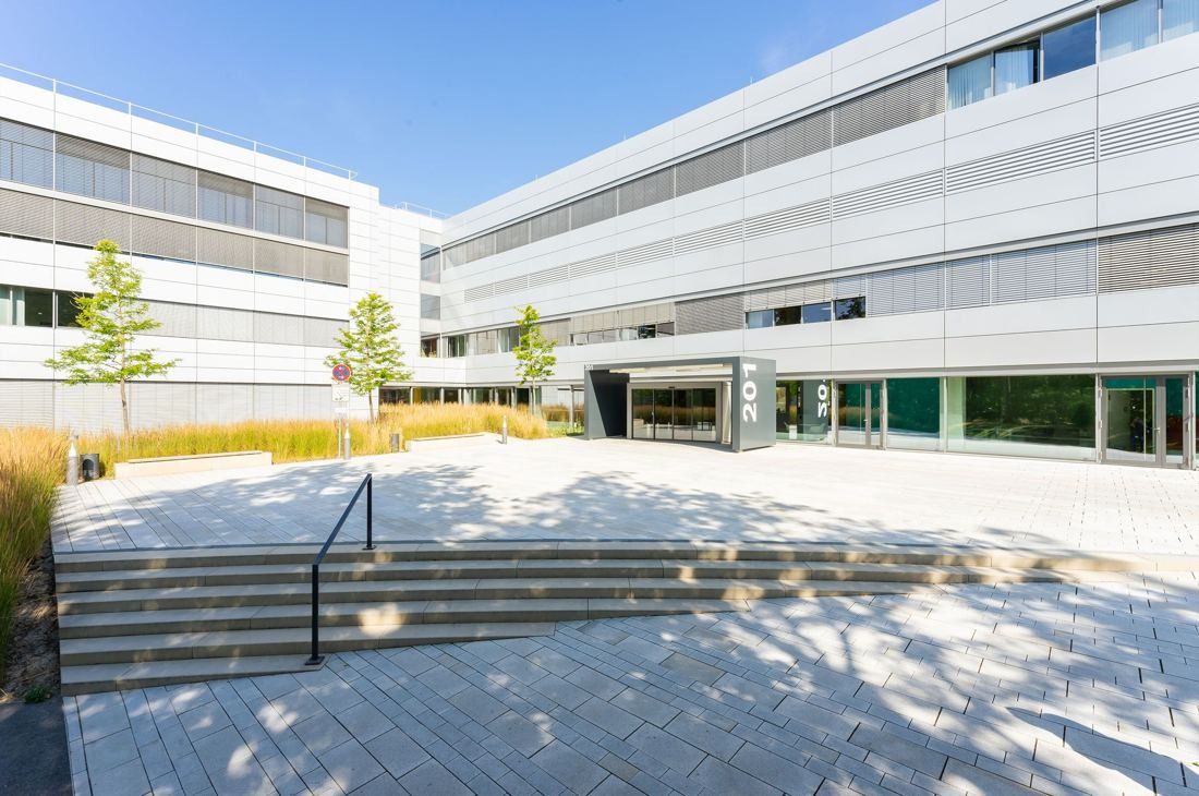Bosch: Paved forecourt with steps leading to a long white-and-grey office building with a glazed entrance