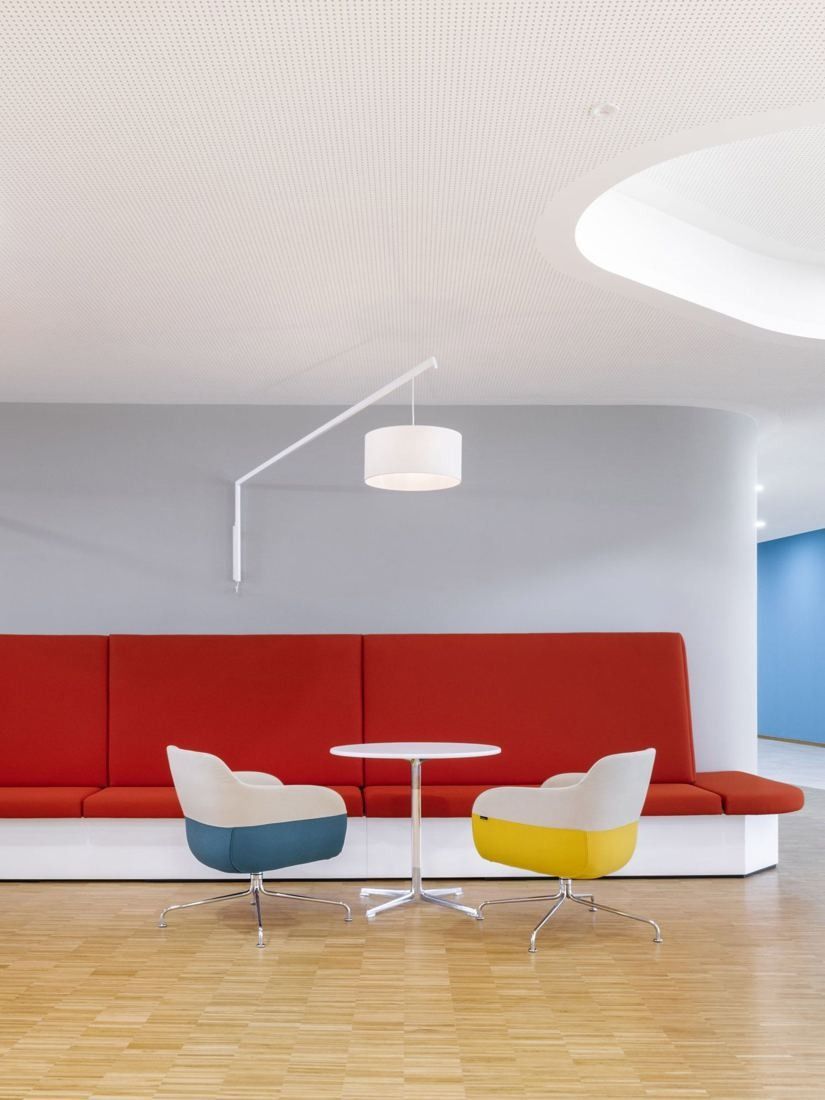 Bosch: Red booth seating with a small round table and two shell chairs in yellow and blue