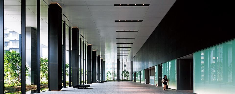 Bridgestone: A long covered colonnade with dark columns and planting beside the building