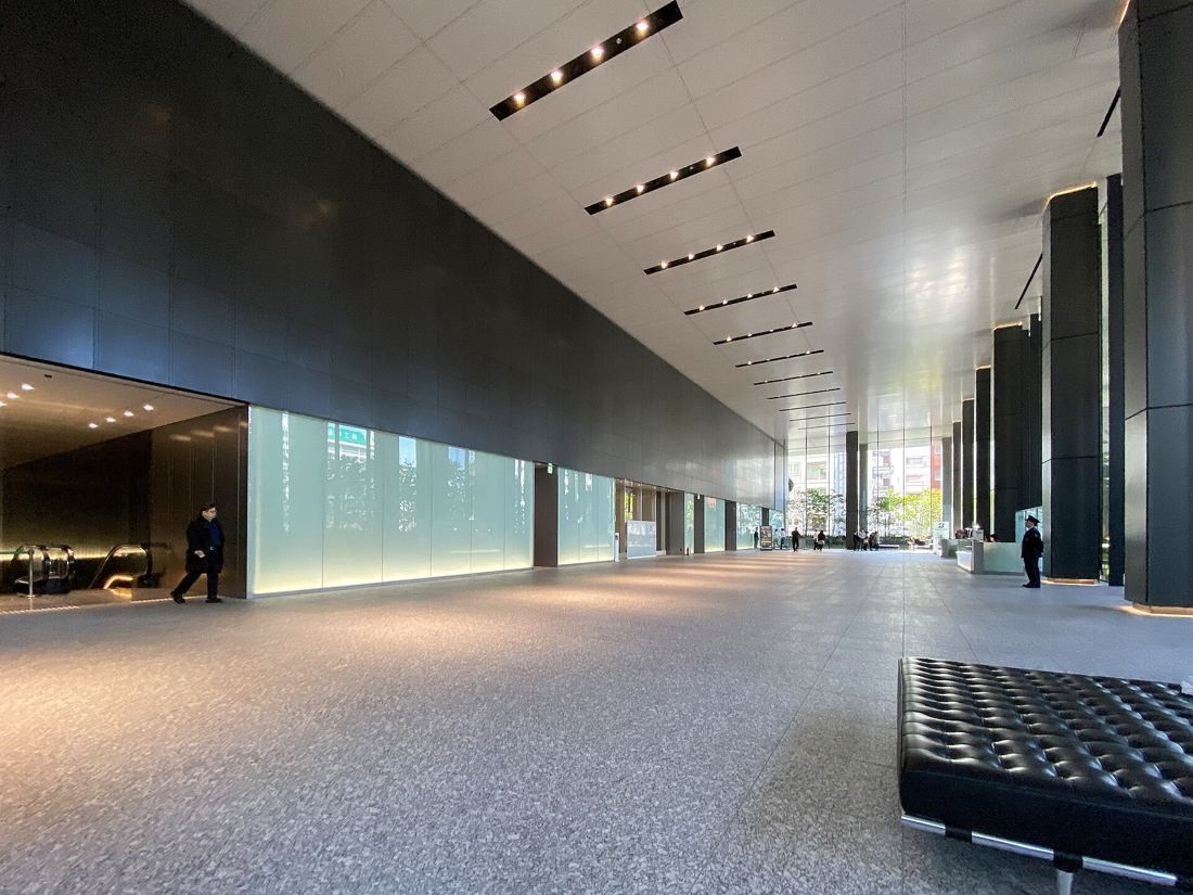 Bridgestone: A long, high-ceilinged lobby with stone floor and backlit glass walls