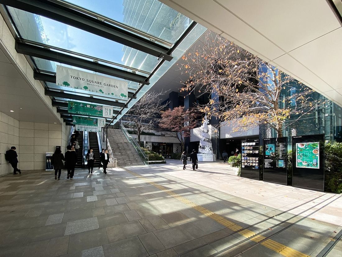 Bridgestone: An open plaza under a glass canopy with escalators and stairs leading up to street level