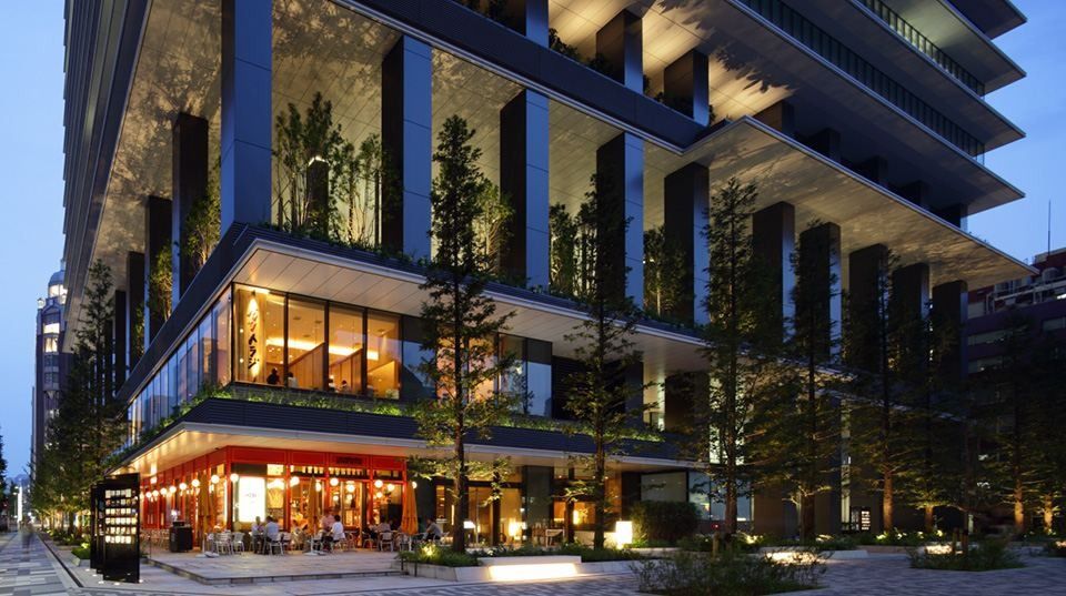 Bridgestone: Lit restaurants and planted terraces at the base of the tower in the evening