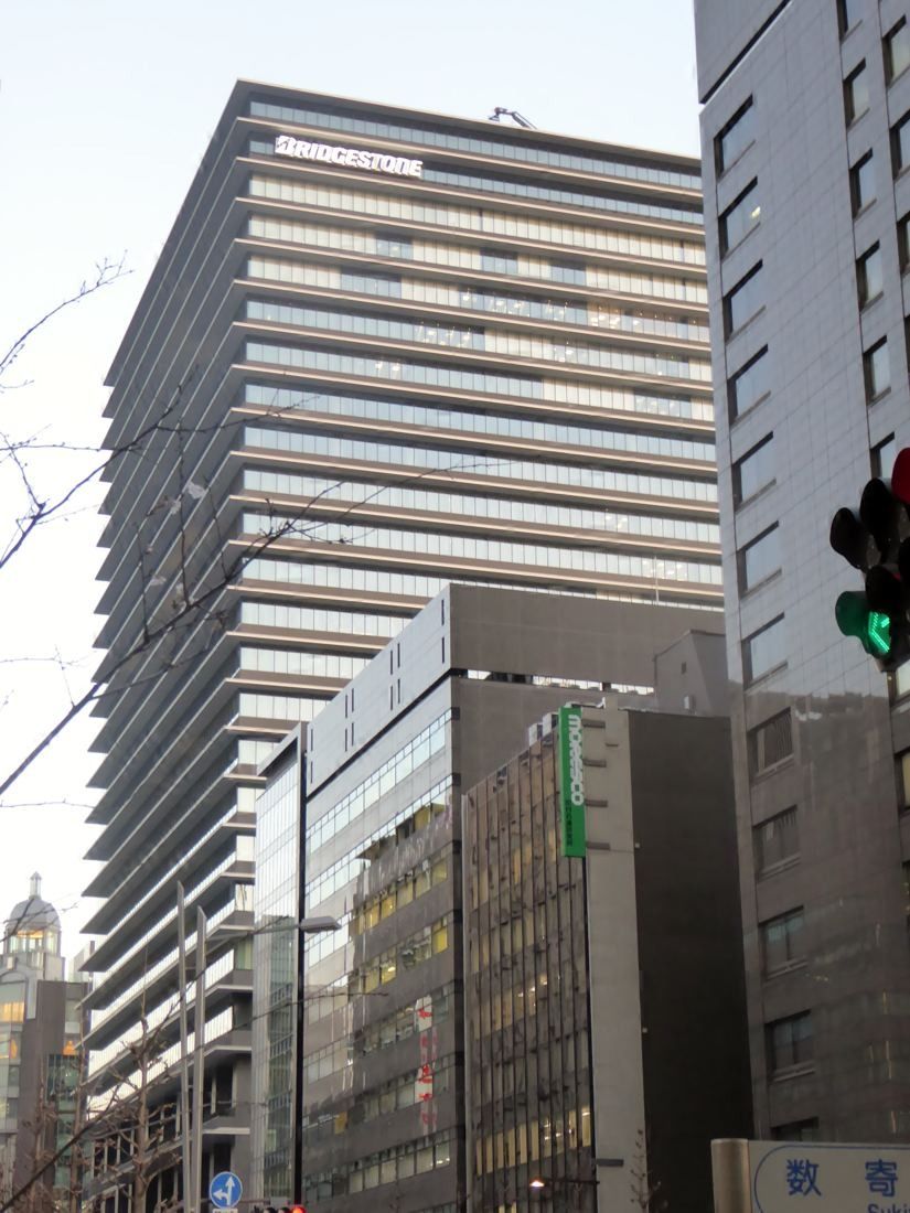 Bridgestone: The tower rising behind neighbouring buildings along a street