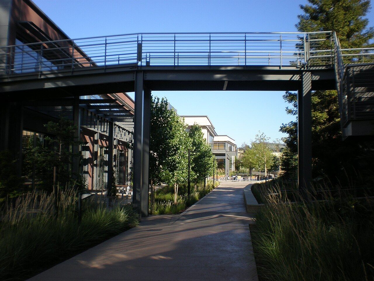 A footbridge between buildings over a garden path