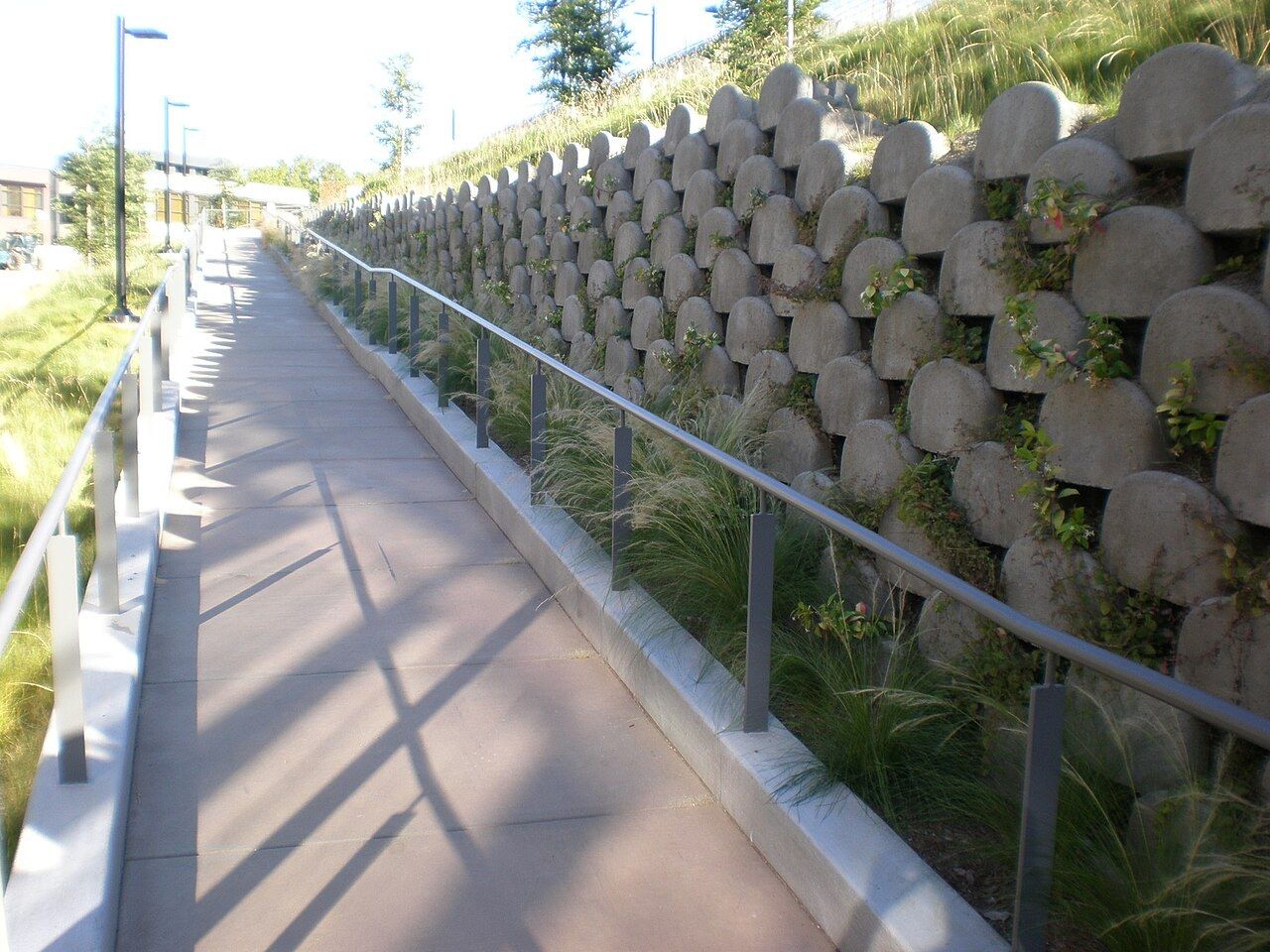 A ramp from the parking lot past a planted wall