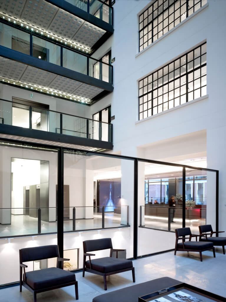 Burberry: Atrium with stacked black-edged bridges above a lounge of dark armchairs and glass partitions