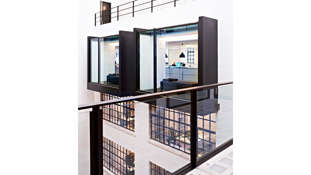 Burberry: Black-framed glazed bays projecting from a white atrium wall, with a glass balustrade in the foreground