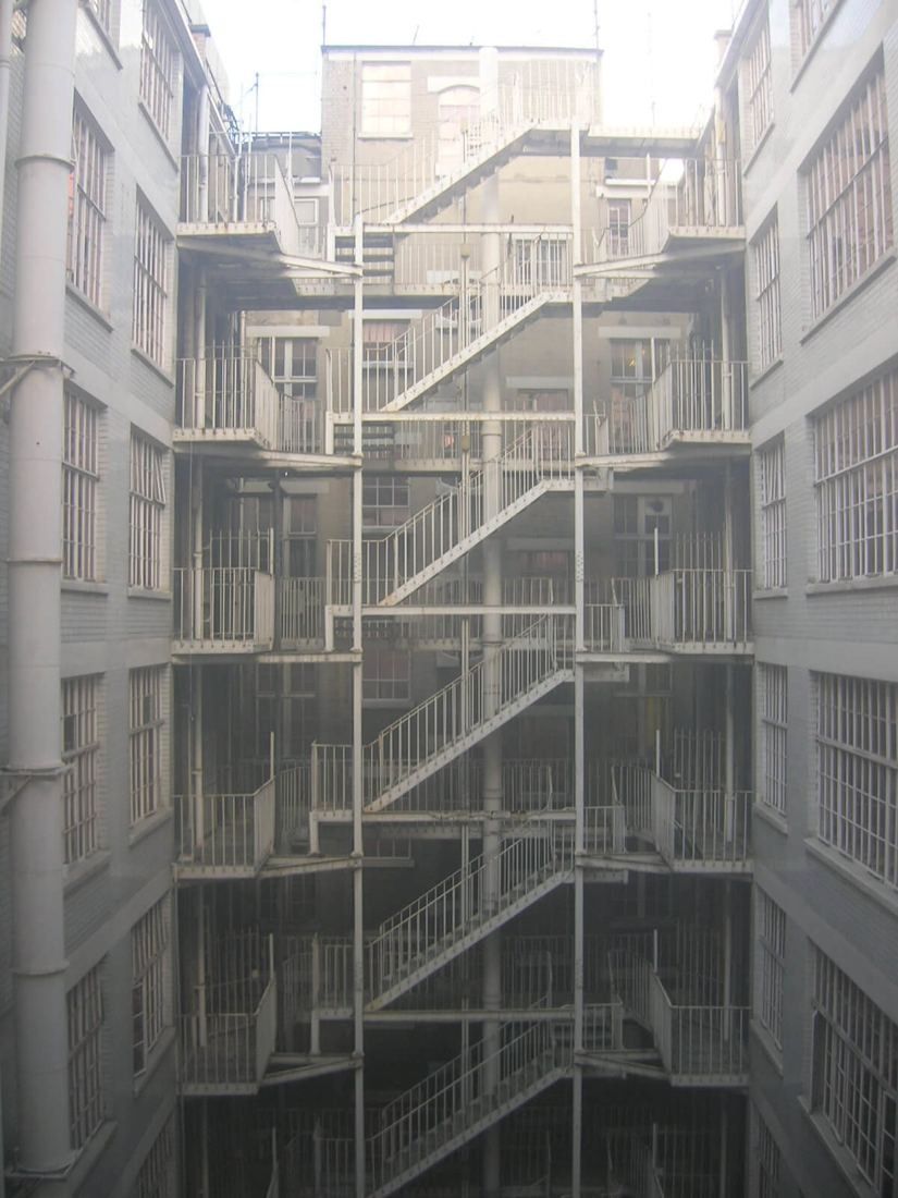 Burberry: Grey lightwell with stacked external steel fire stairs between rows of old windows