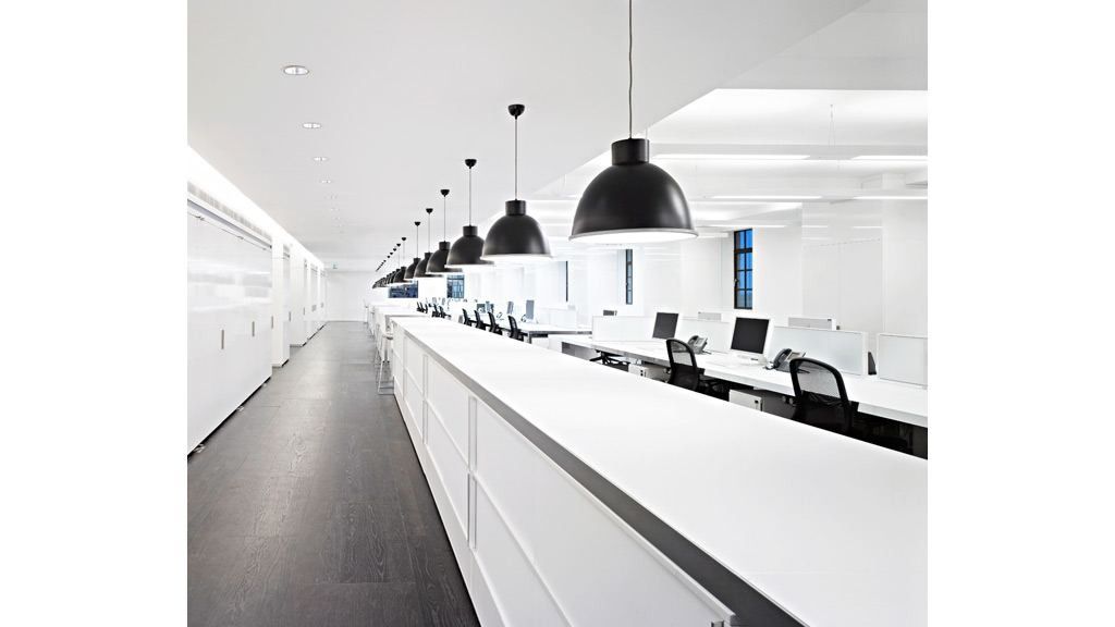 Burberry: Long white workbench with monitors under a row of black pendant lamps