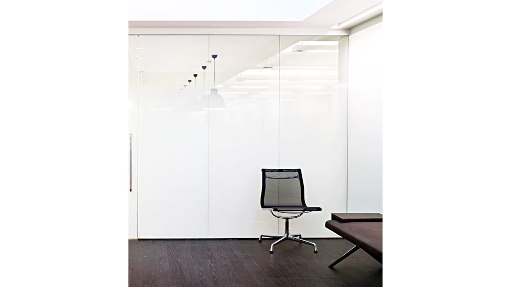 Burberry: Minimal white room with a single mesh office chair and dark floor