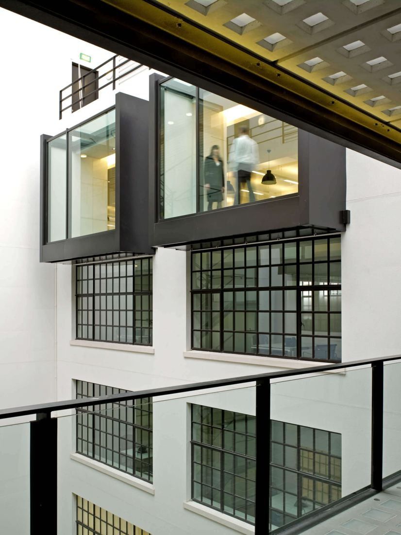 Burberry: Two black-framed glass boxes projecting into a white atrium above gridded windows, seen from a bridge