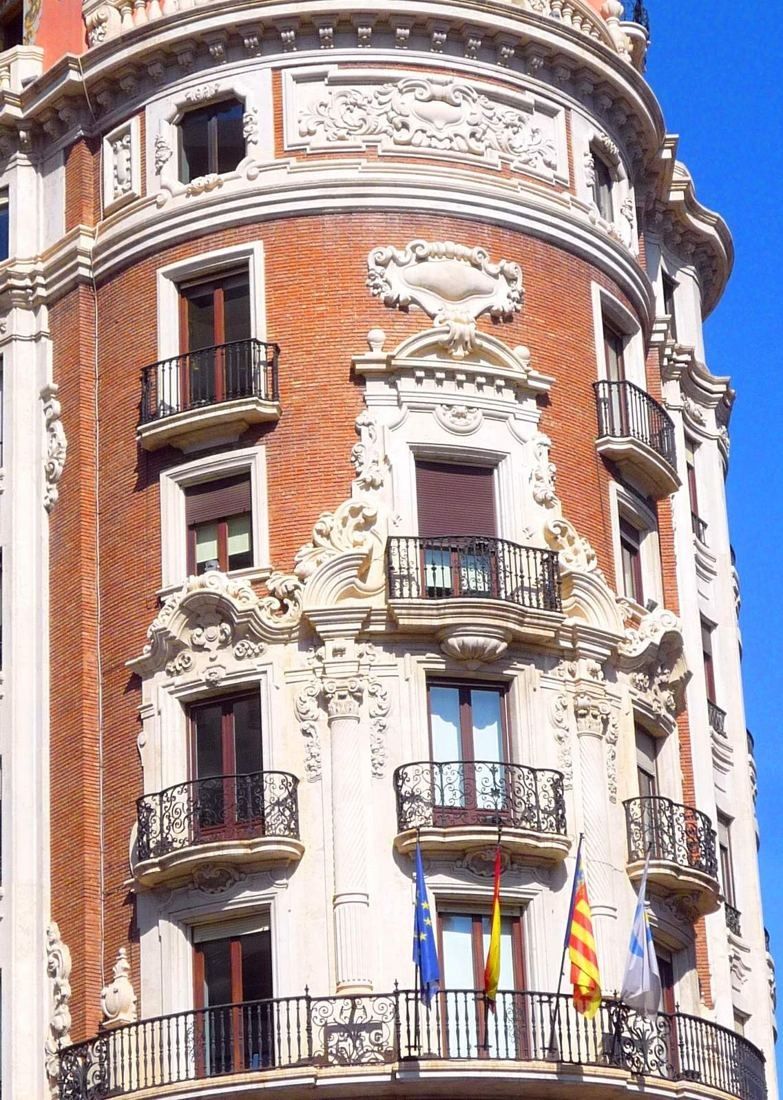 CaixaBank: Brick and white stone ornament around windows and balconies with flags
