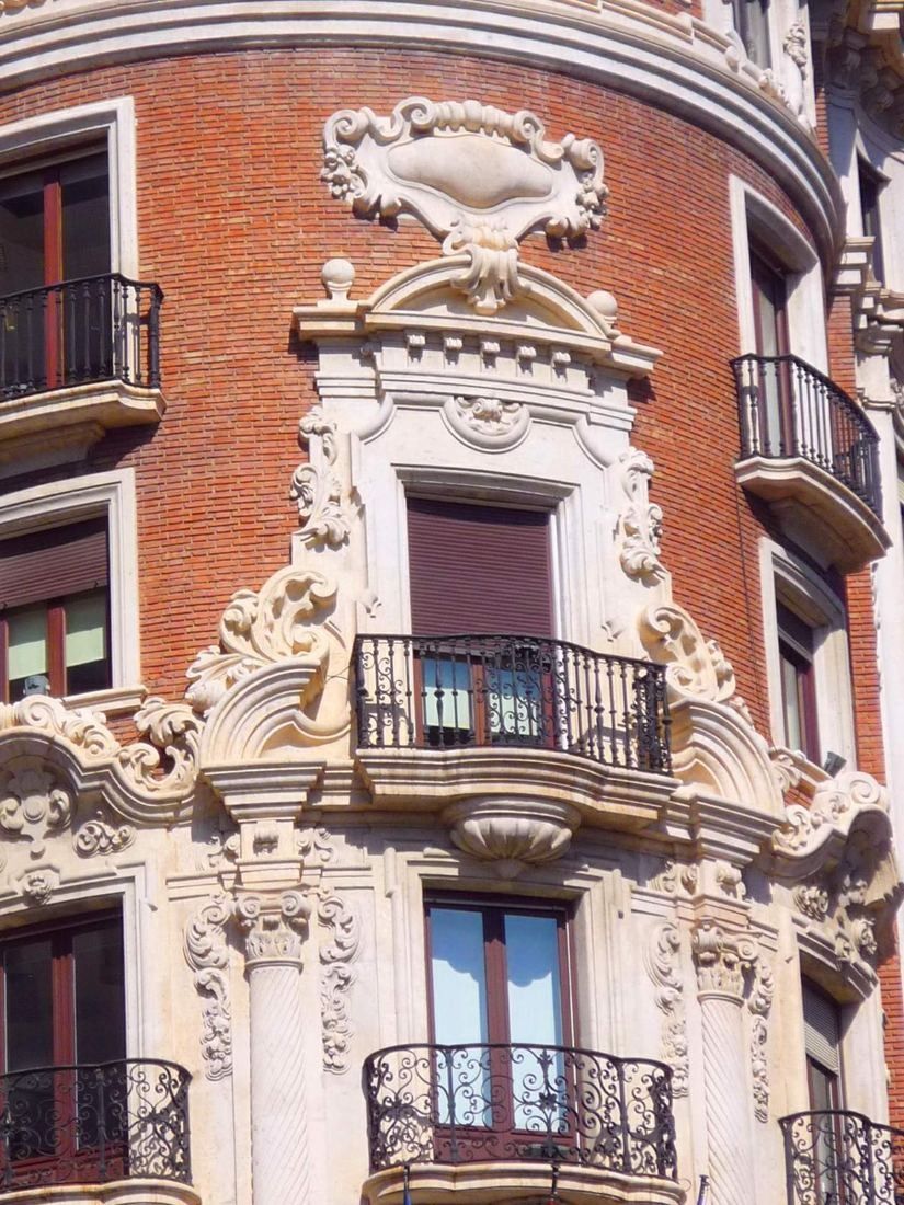 CaixaBank: Close view of carved white stone ornament framing windows on brick