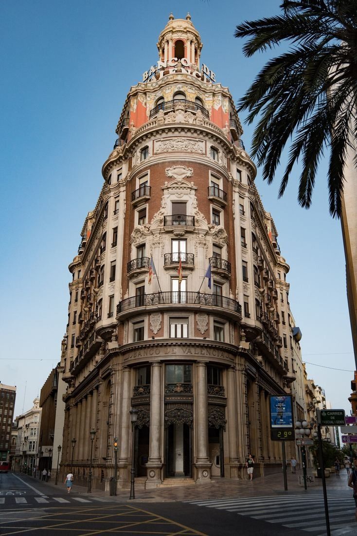 CaixaBank: Tall view of the rounded corner rising from a colonnaded base, palm fronds at the edge