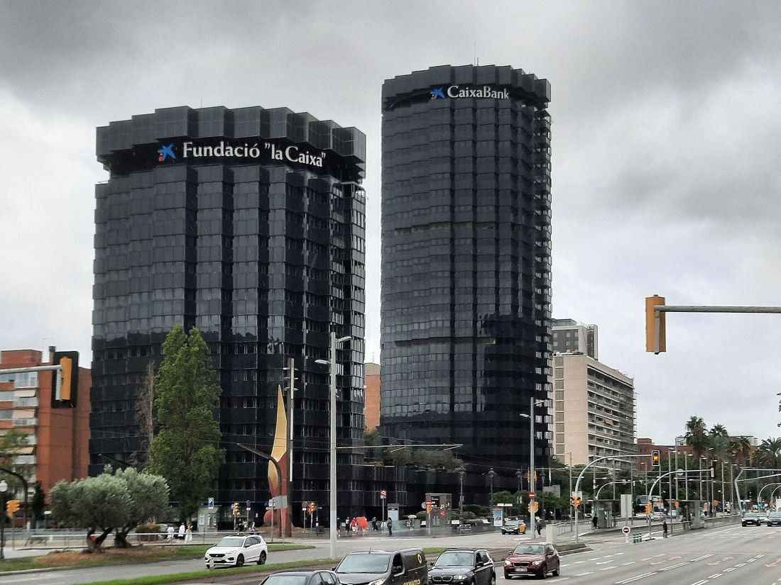 Two dark glass cylindrical towers beside a wide avenue