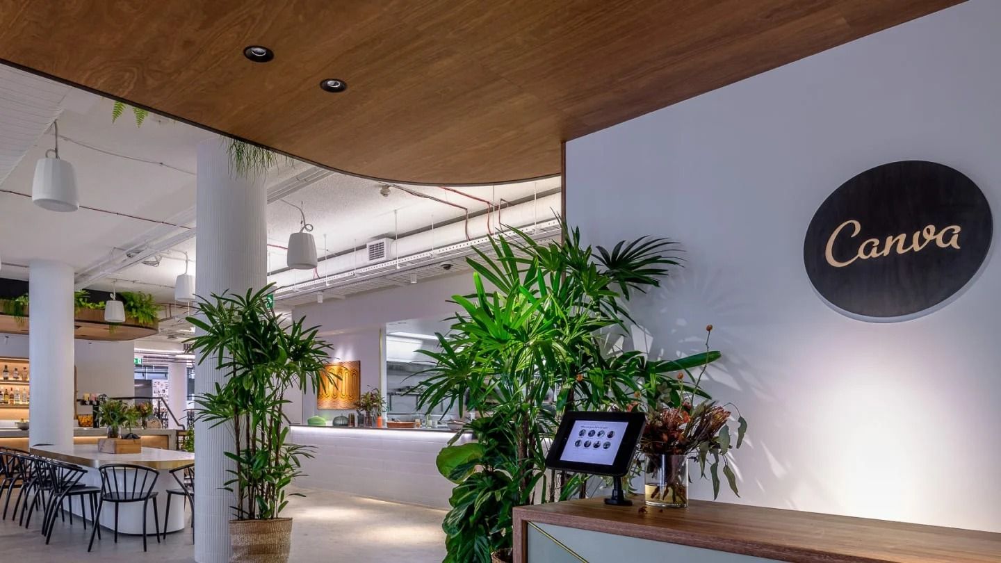 Canva: Reception desk beside a white wall with the Canva logo and palms