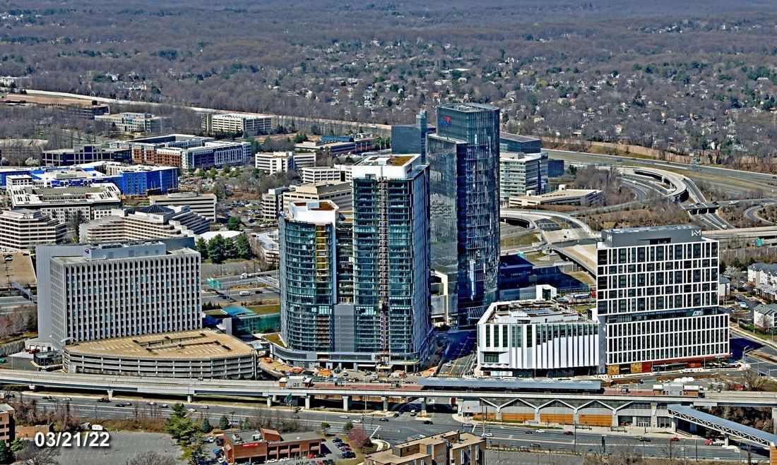 Capital One: Aerial view of glass towers and low buildings beside elevated rail