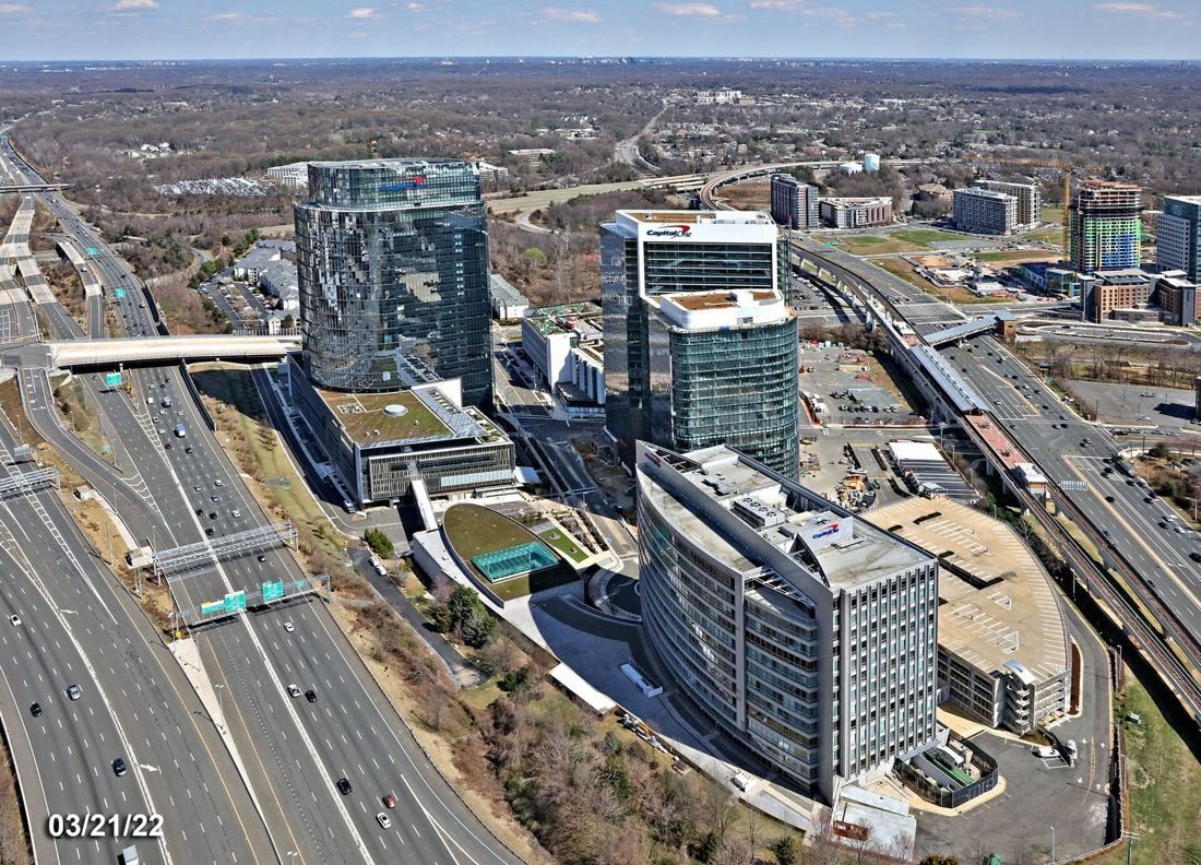 Capital One: Aerial view of glass towers beside a multi-lane highway and rail line