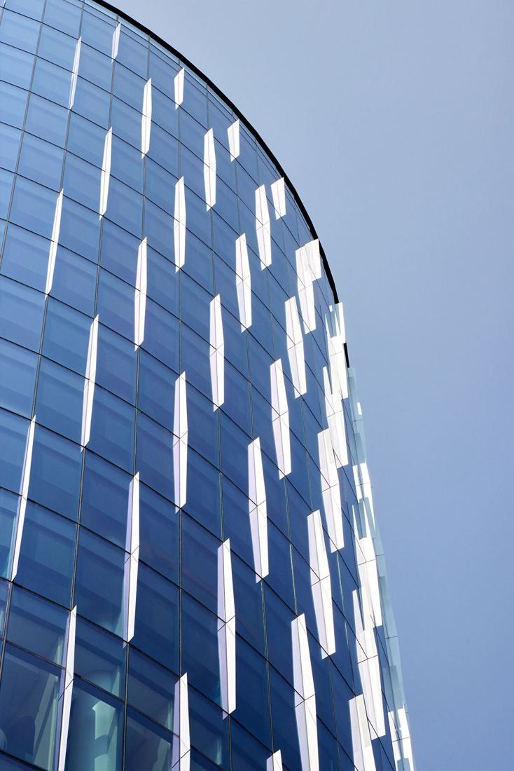 Capital One: Close view of a curved blue glass facade against the sky