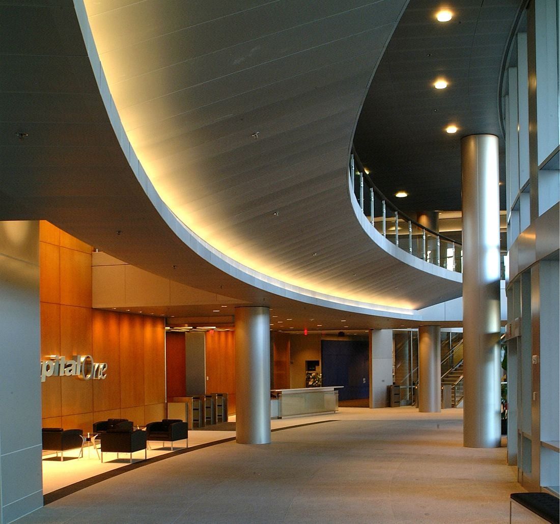 Capital One: Curving lobby with wood walls, columns and a lit ceiling band