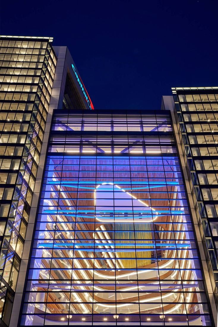 Capital One: Glass atrium between two towers lit at night, wood balconies visible inside