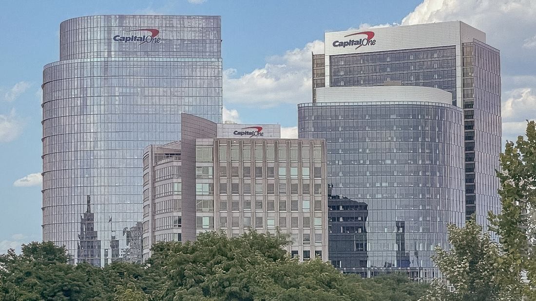 Capital One: Several glass office towers with signs on their crowns above trees